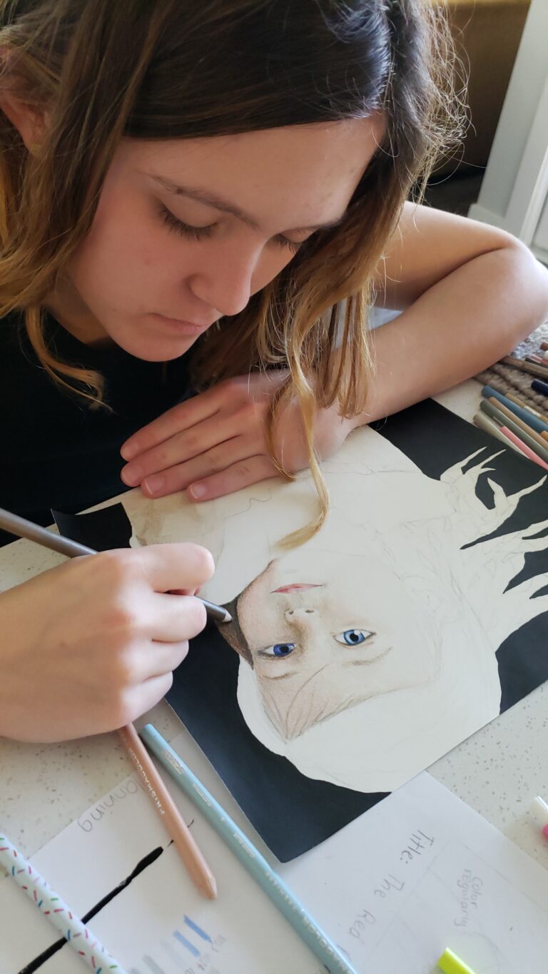 Teen girl drawing a realistic portrait of her younger sister using colored pencils